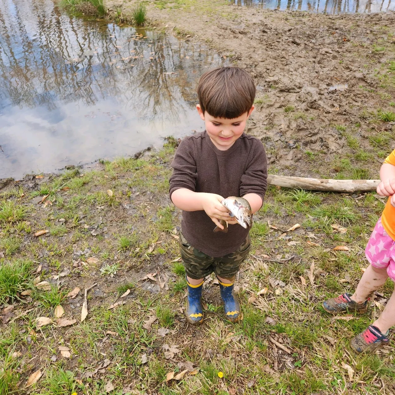 A boy and girl holding fish in their hands.