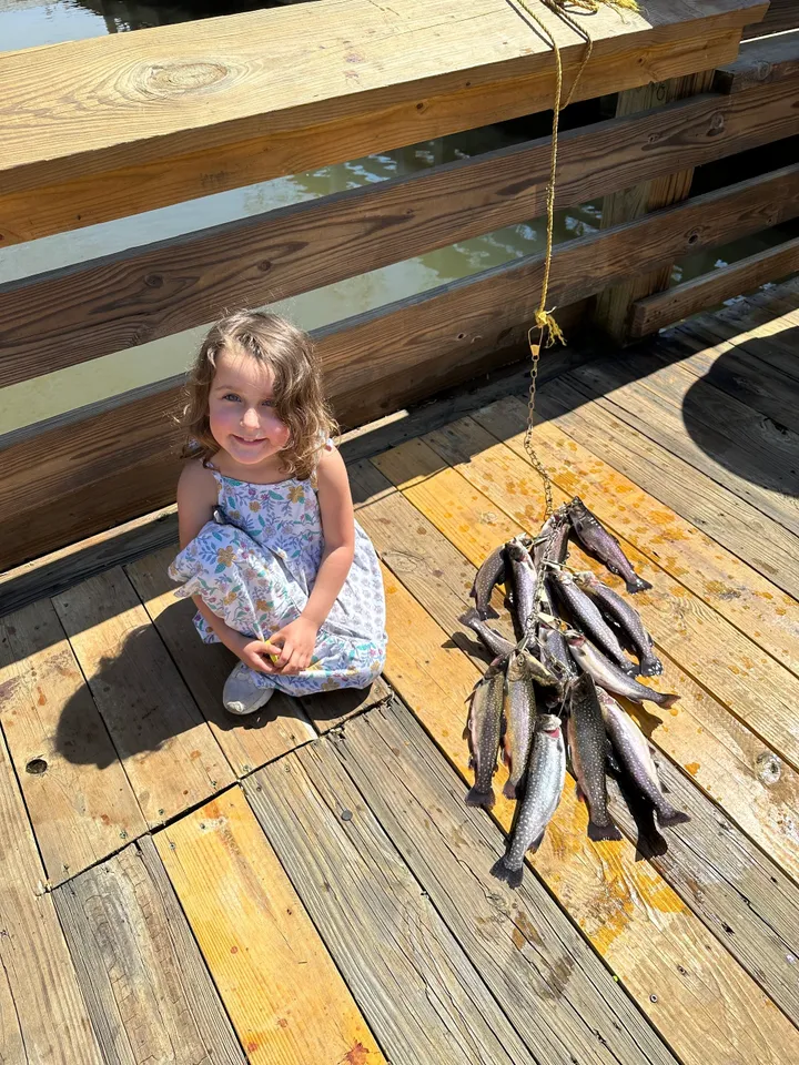 A little girl sitting on the ground next to some fish.