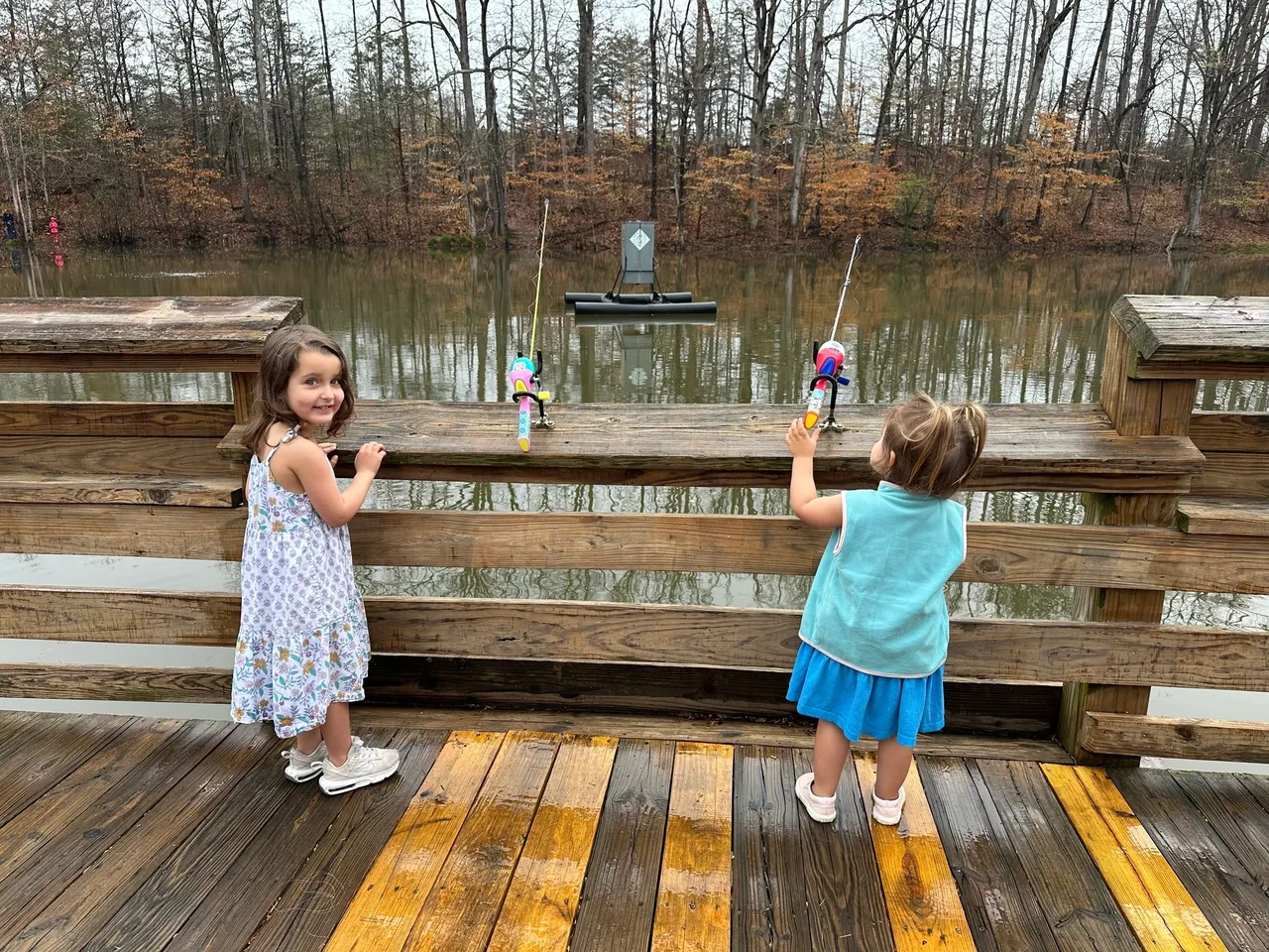 Two little girls fishing on a pier.