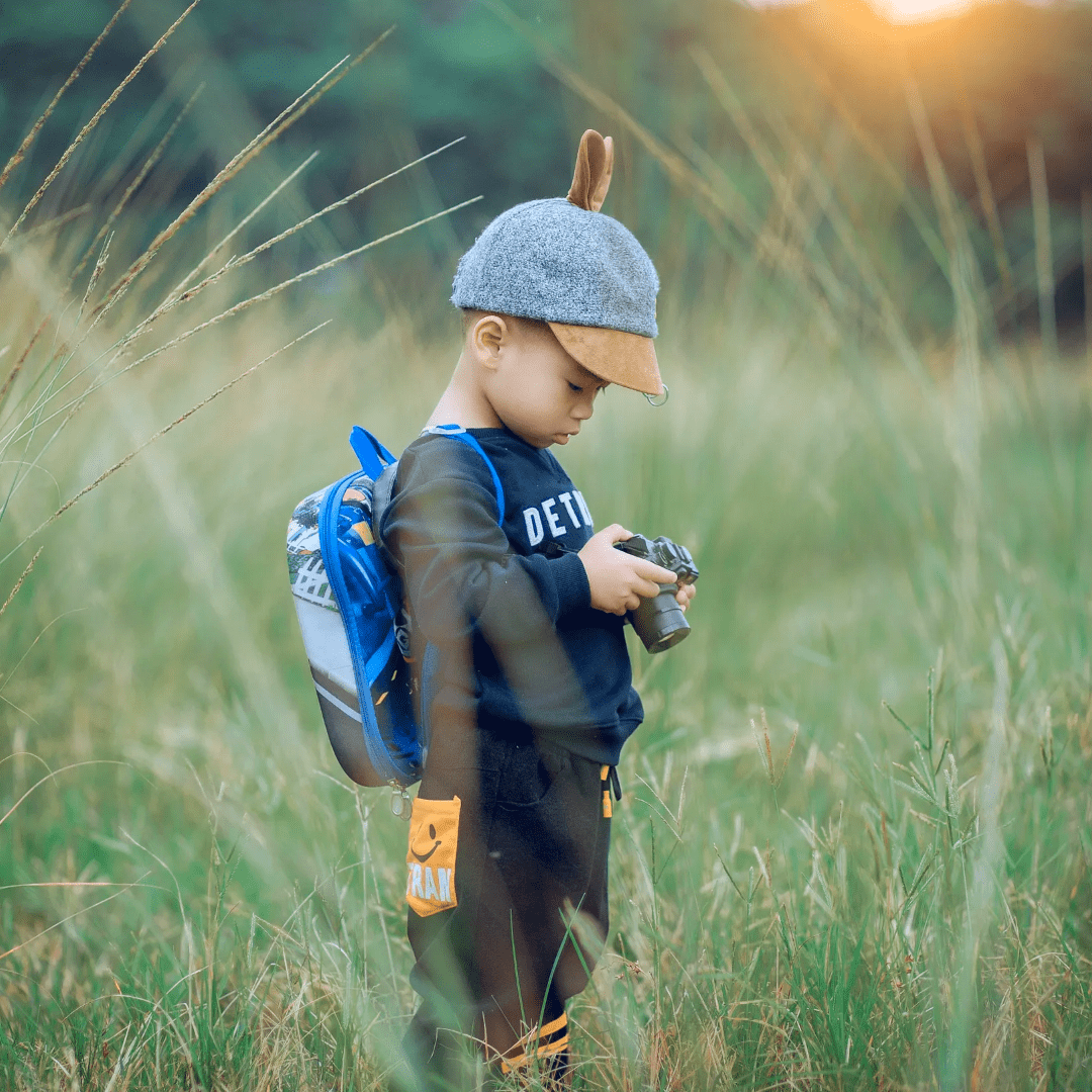 A young boy in the grass looking at his phone.