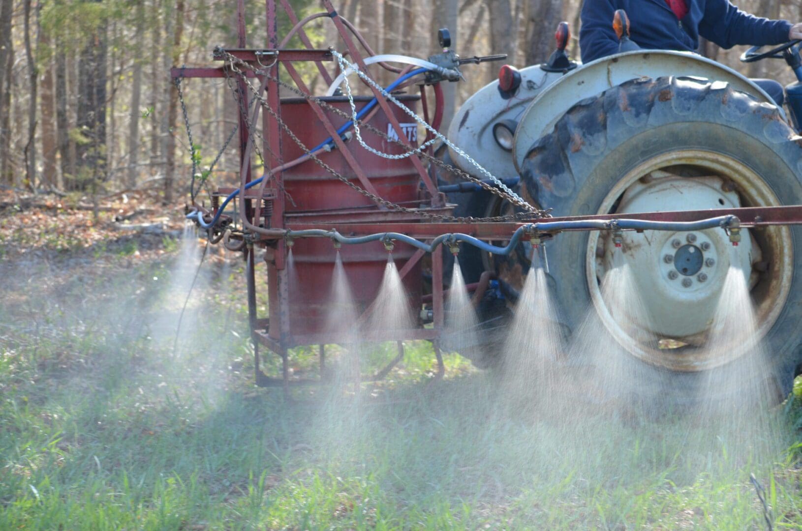 A tractor spraying pesticide on the ground.